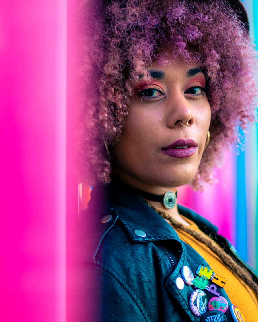 A portrait of a woman with a curly afro against neon light