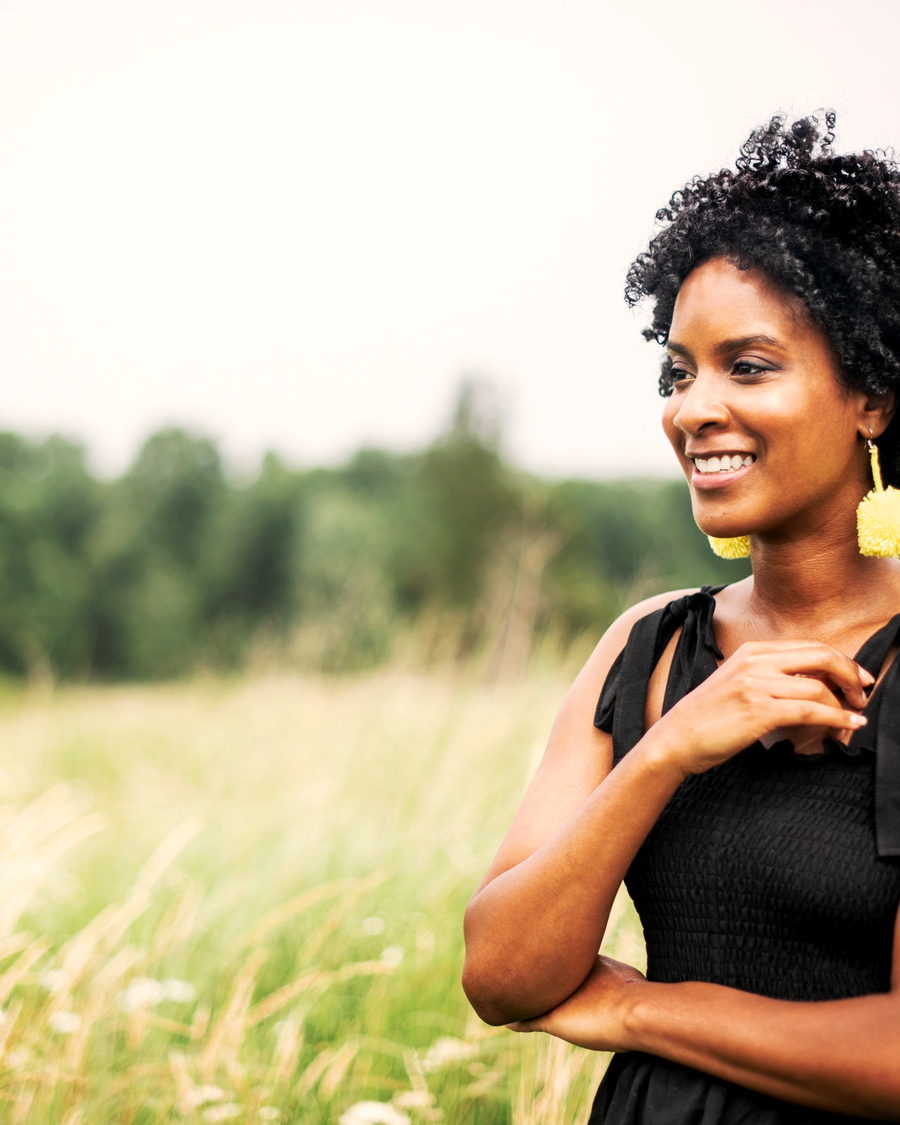 A woman with a short natural afro standing in a field
