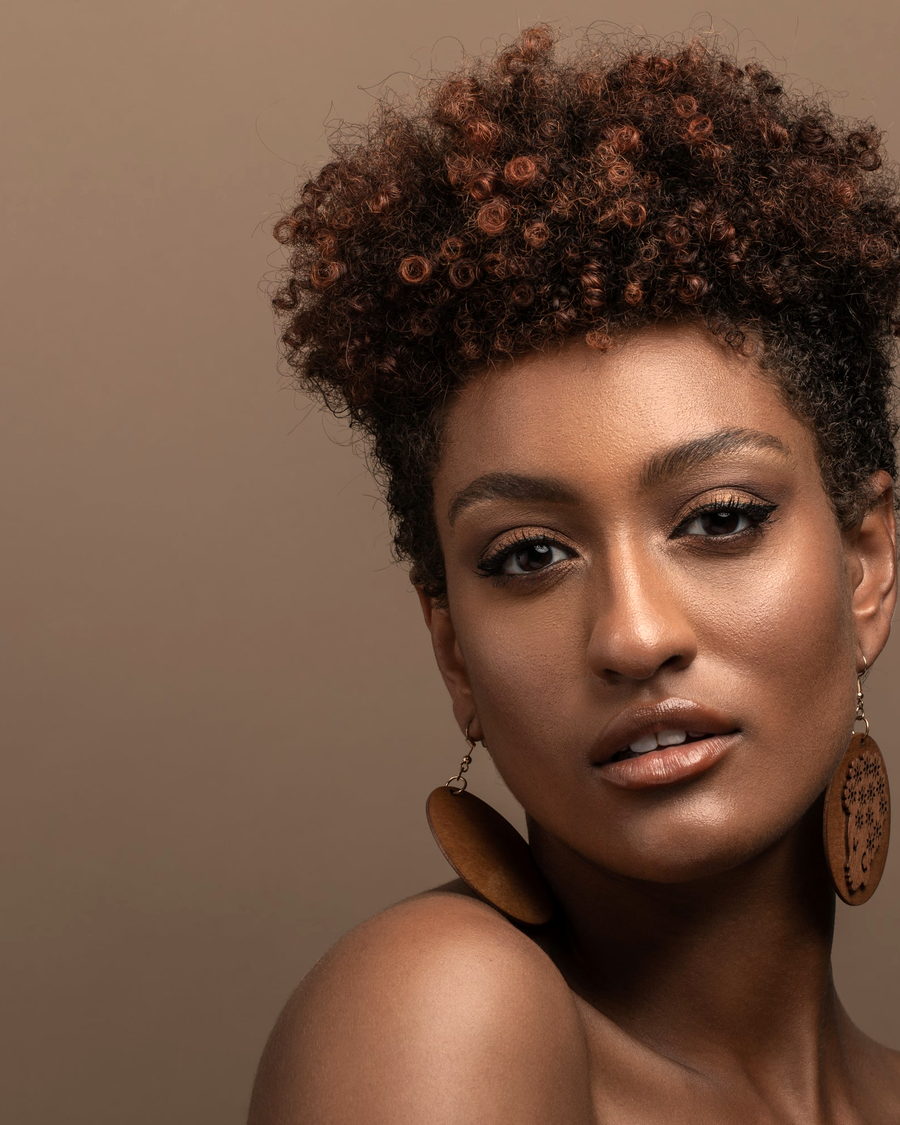 A studio portrait of a woman with a short natural afro