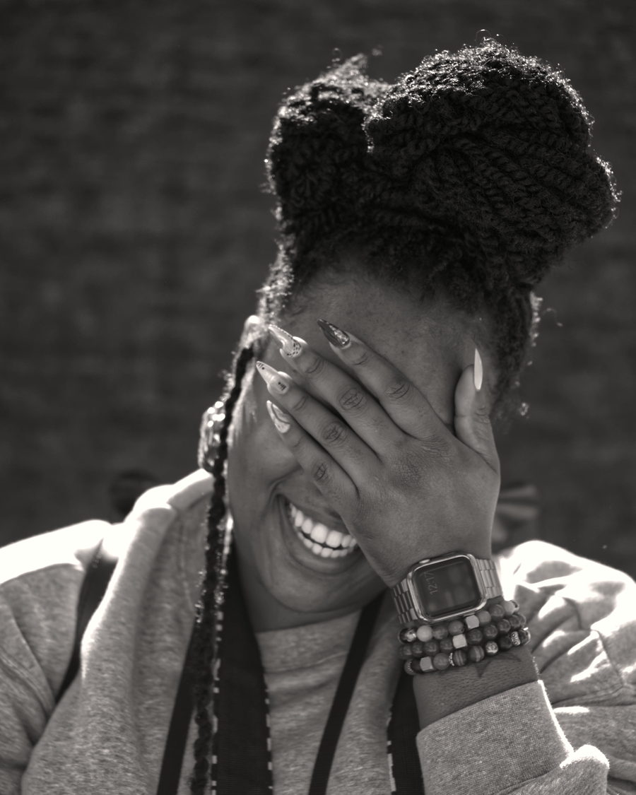 A woman with braids covering her face with one hand