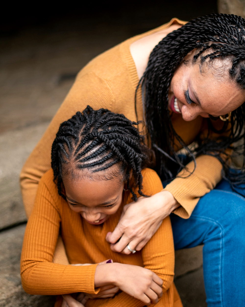 A mother holding her daughter, both in cornrows