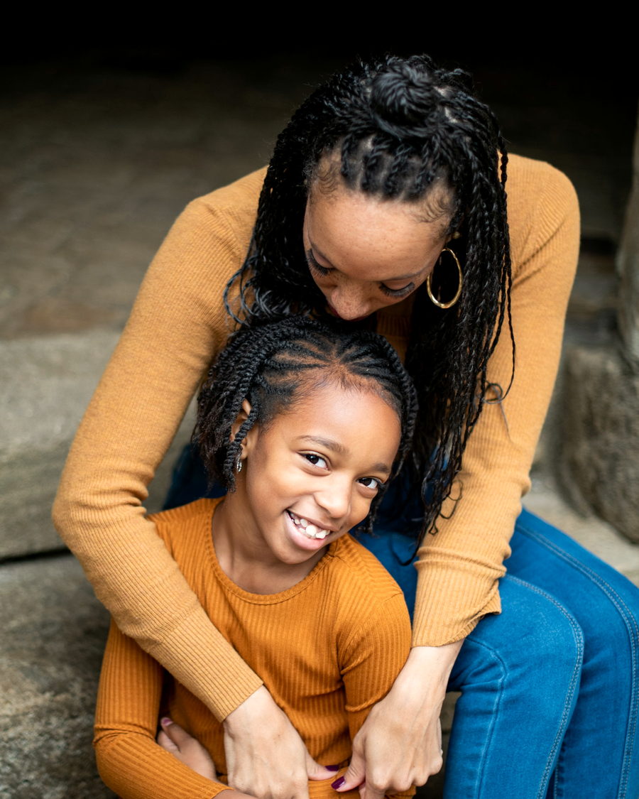 A mother and daughter laughing together, hair in braids
