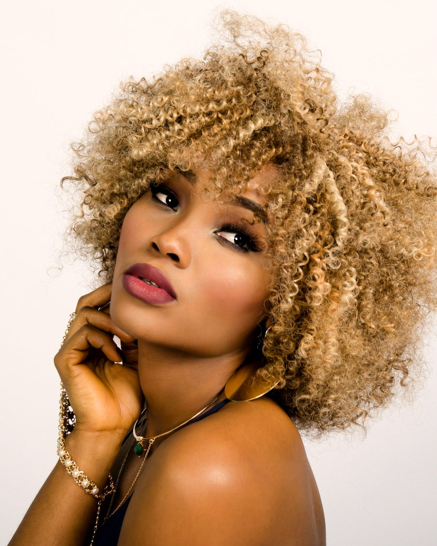 A close portrait of a woman with tight blonde curls
